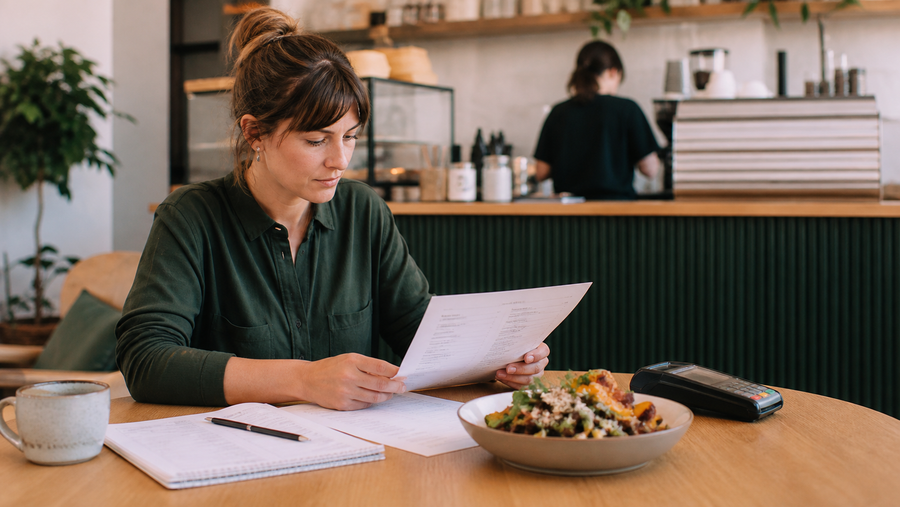 Australian café owner reviewing menu prices, recipe costs and operating expenses at a table